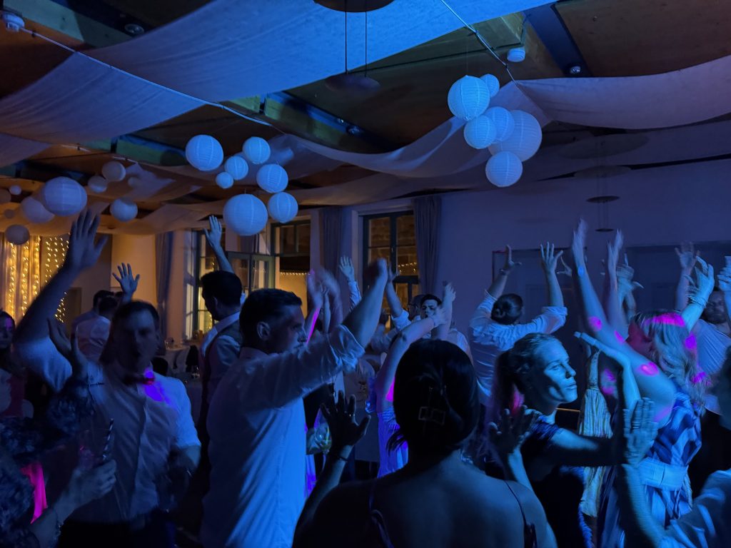 Hochzeitsgäste feiern ausgelassen in Nürnberg mit erhobenen Händen, DJ eMPi sorgt für Stimmung.